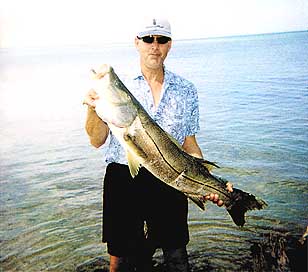 Standing nearly knee deep in water on a sand bar is Chuck Allen displaying the snook he caught in San Carlos Bay on May 10. Allen was wading around the sand bars and saw the large fish shadow. The snook was caught on a 9-weight fly rod, with a grey/silver whistler fly his wife Ginger tied for him. The catch weighed in at 26 pounds and was 47 inches long. The snook was beached and released successfully. Special to the Eagle